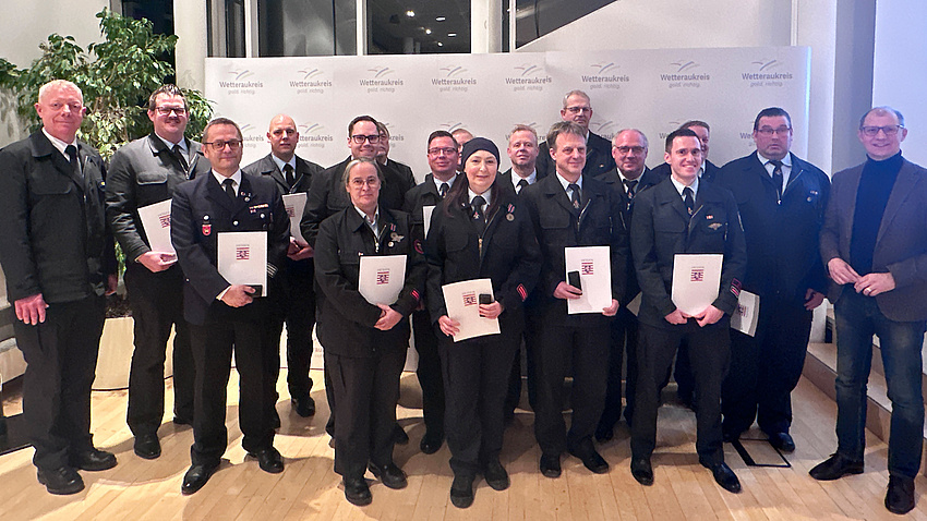 Mehrere Personen halten Urkunden in den Händen und schauen in die Kamera.