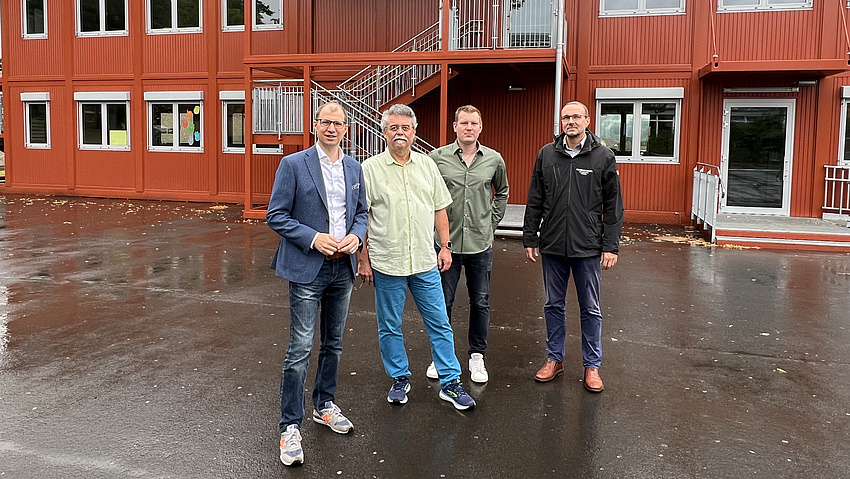 Die vier Herren vor dem roten Gebäude.