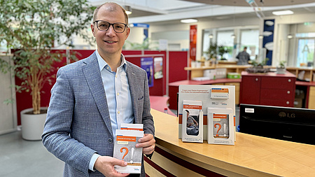 Landrat Jan Weckler steht an einem Tisch. Er hält einen Flyer zum Thema Organspende in die Kamera.