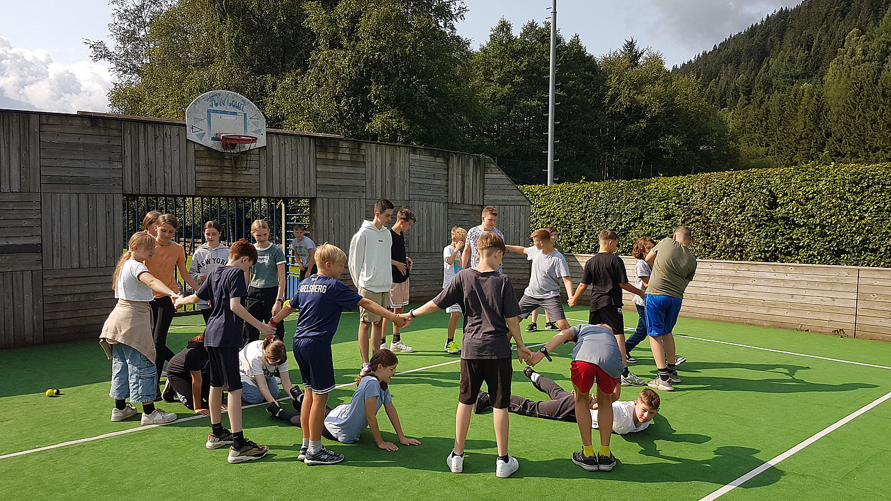 Viele Jugendliche auf einem Basketballfeld im Freien