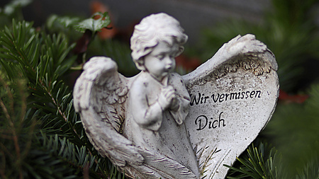 Ein Engel aus Stein, auf einem Flügel steht: "Wir vermissen dich"