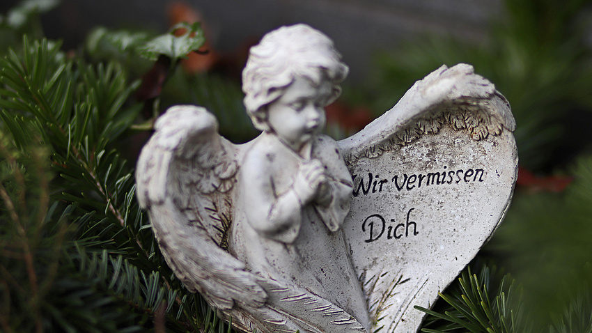 Ein Engel aus Stein, auf einem Flügel steht: "Wir vermissen dich"