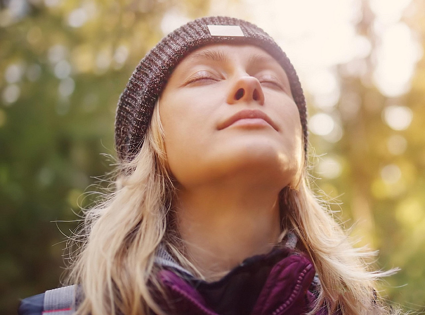 Kopf einer Frau mit Mütze und geschlossenen Augen in freier Natur.