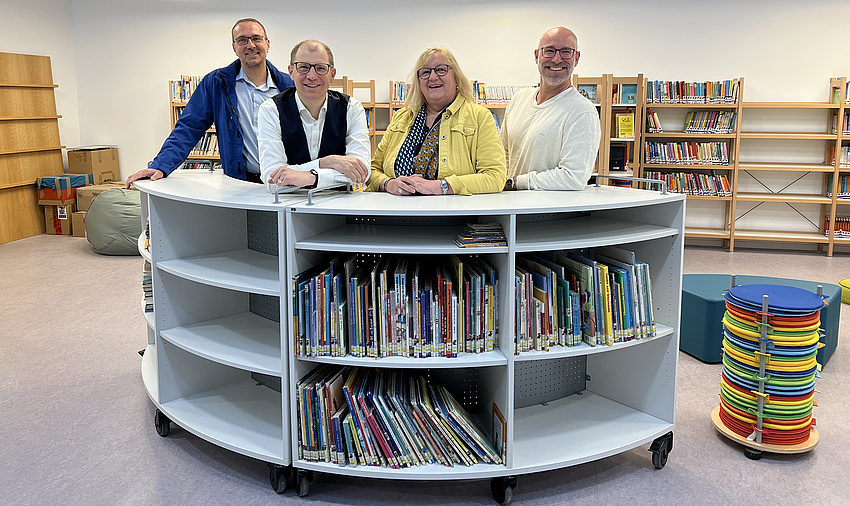 Die Menschen stehen hinter einem halbrunden Büchercontainer.