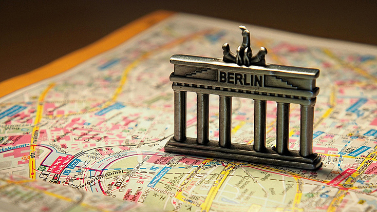 Auf einem Stadtplan von Berlin steht eine Miniatur der Brandenburger Tors.