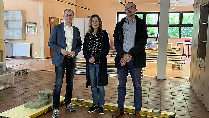 Die drei stehen auf der Baustelle.