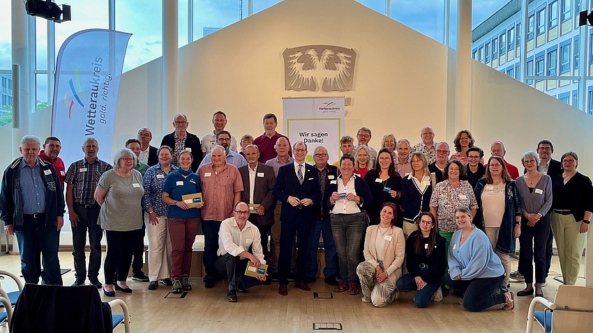 Eine große Gruppe von Menschen steht in einem Versammlungssaal.