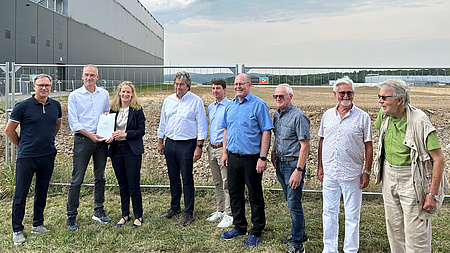 Eine Gruppe von Menschen steht auf einem Acker.