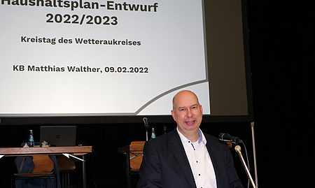 Finanzdezernent Matthias Walther, im Hintergrund auf der Leinwand die Präsentation des Haushaltsentwurfs.