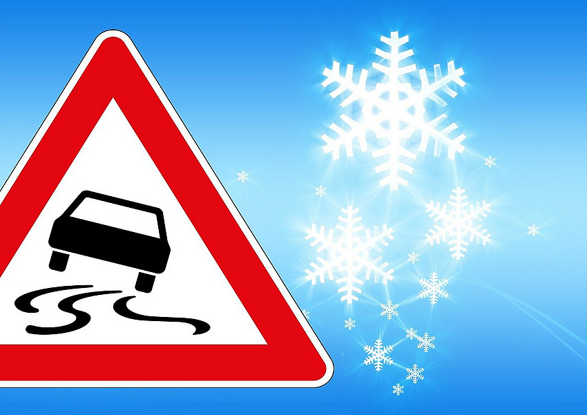 Symbolbild: Verkehrsschild mit einem schlingernden Auto. Im Hintergrund stilisierte Schneeflocken vor eisblauem Hintergrund.