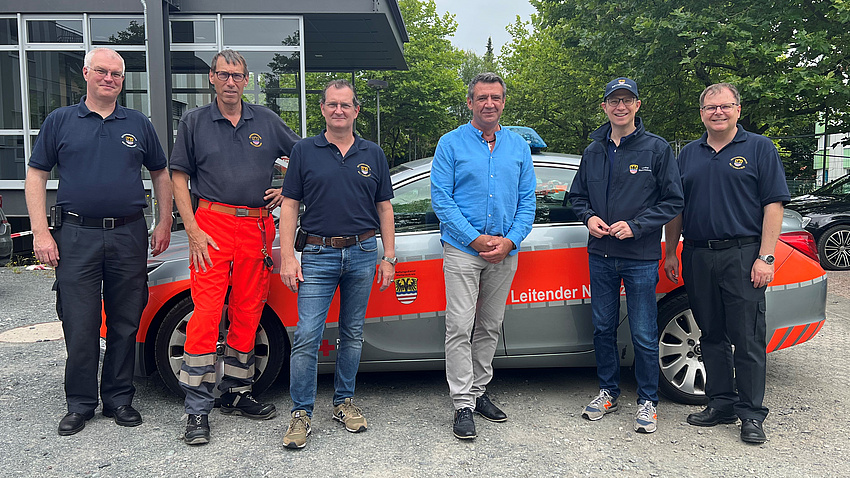 Landrat Jan Weckler steht mit fünf weiteren Männern vor einem Einsatzfahrzeug.