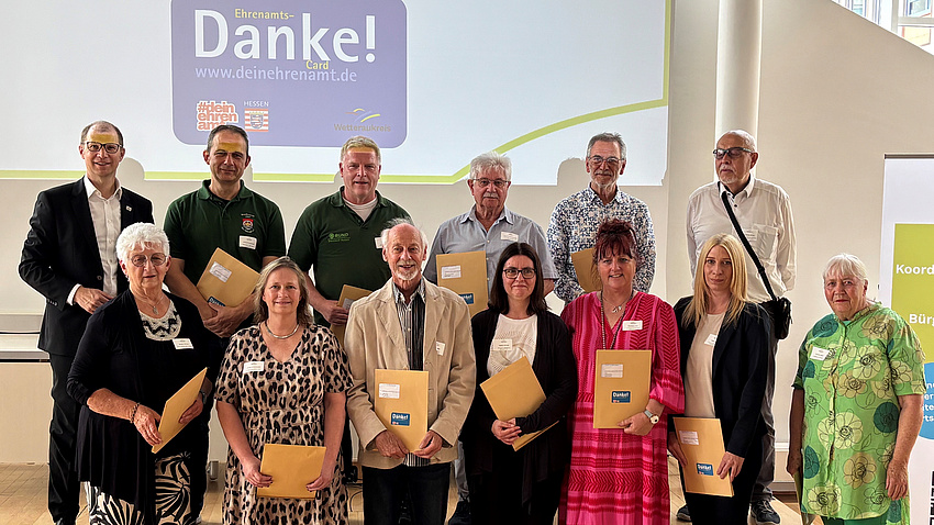 Zwölf Menschen stehen vor einer Wand, auf der Danke steht.