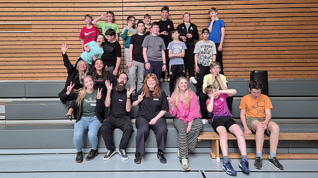 Eine Gruppe von Jungen und ihren Betreuern in einer Turnhalle. Sie lachen in die Kamera.