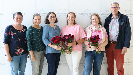 Fünf Frauen und ein Mann lächeln in die Kamera.