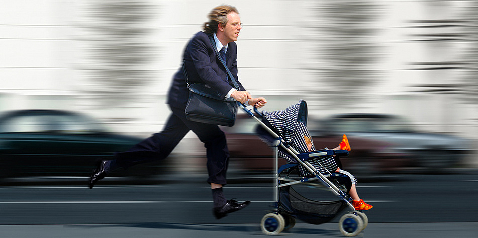 Ein Vater rennt mit seinem Sohn im Kinderwagen durch die Stadt 