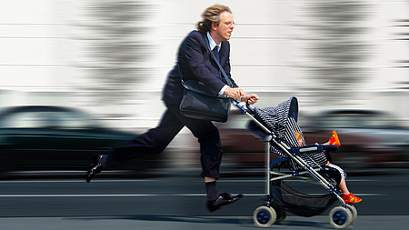 Ein Vater rennt mit seinem Sohn im Kinderwagen durch die Stadt