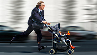Mann rennt mit einem Buggy, in dem ein Kind sitz