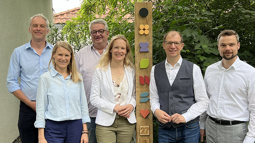 Eine Gruppe von Menschen steht im Grünen.