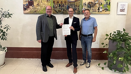 Landrat Jan Weckler mit der dem Zuwendungsbescheid steht in der Mitte.