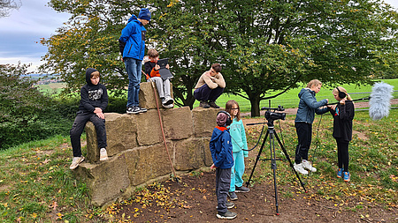 Jugendliche, die mit Kamera-Equipment einen Film drehen in freier Landschaft