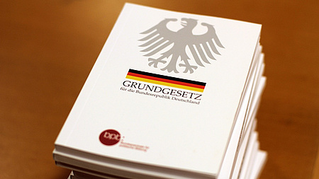 Mehrere Ausgaben des Grundgesetzes liegen auf einem Stapel.