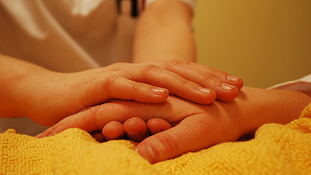 Eine jüngere Hand umschließt eine ältere Hand.