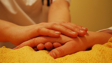 Eine jüngere Hand umschließt eine ältere Hand.