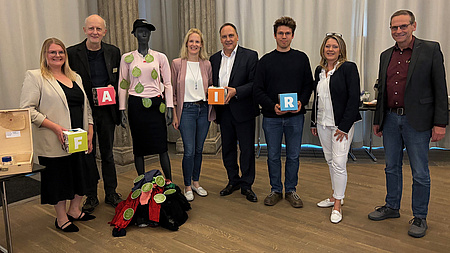 Eine Gruppe von Leuten mit einer Schaufensterpuppe, die Kleidung präsentiert.