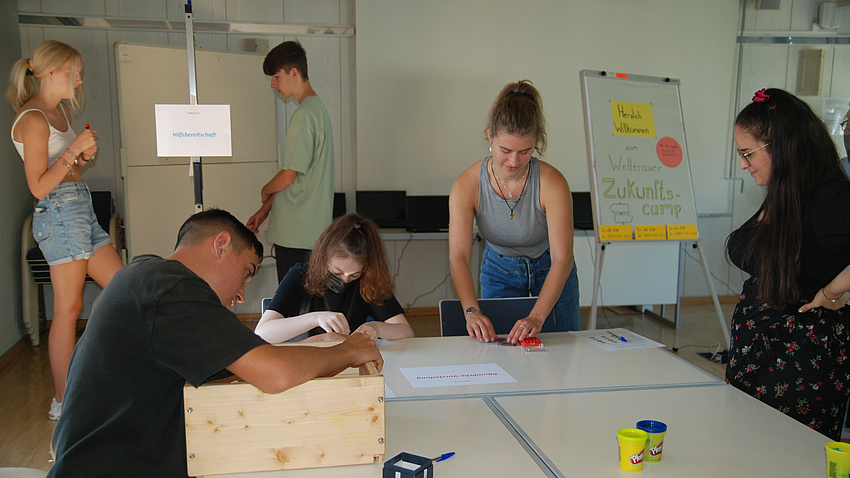 Fünf junge Leute in einem Seminarraum.
