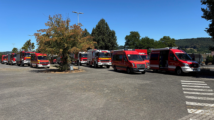 Mehrere Feuerwehrfahrzeuge stehen auf einem großen Platz unter freiem Himmel.