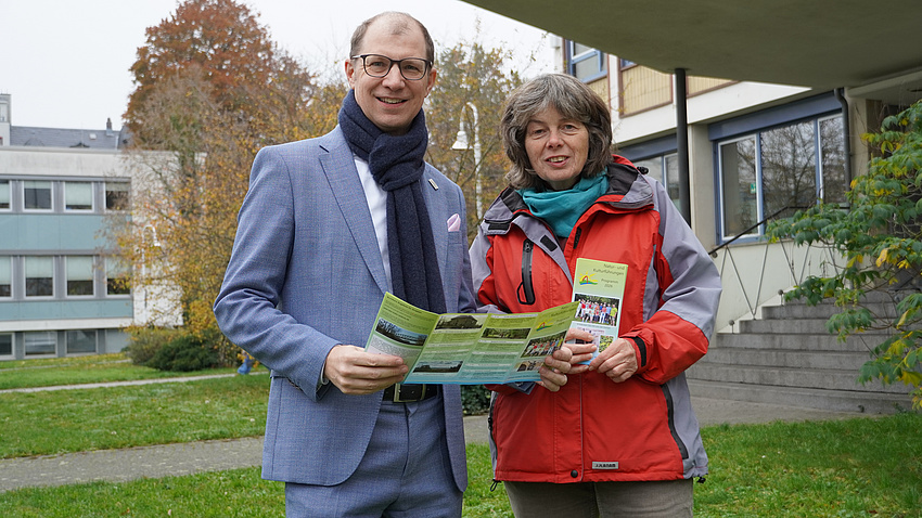 Landrat Jan Weckler und Annette Miksch zeigen einen Flyer.