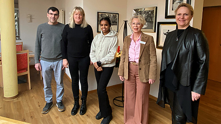 Vier Frauen und ein Mann lächeln in die Kamera.