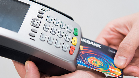 Ein Mann steckt eine Girocard in ein elektronisches Zahlungsgerät.