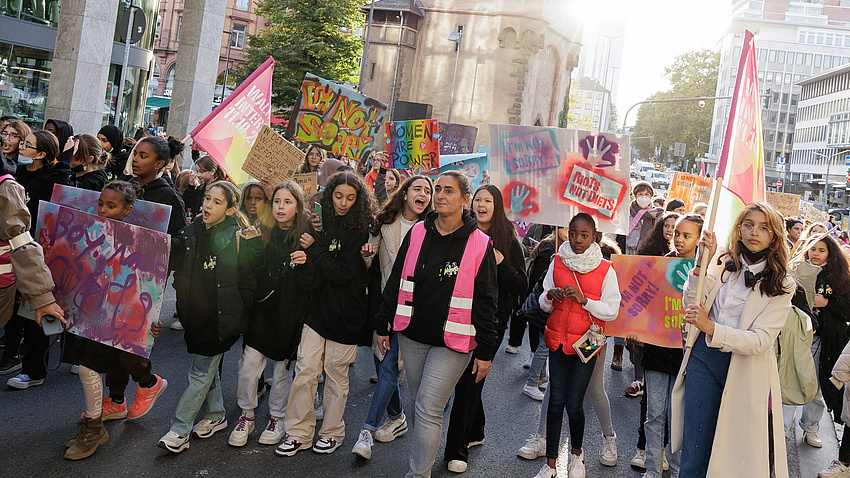 Viele Mädchen laufen mit Plakaten und Fahnen durch die Stadt