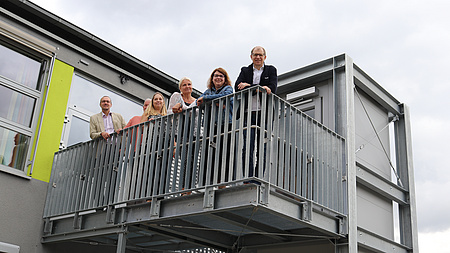 Mehrere Menschen stehen auf einem Hublift, der in den ersten Stock gefahren ist.