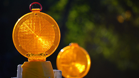 Zwei Warnbaken stehen im Freien hintereinander.