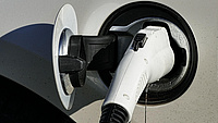 Der Ladestecker einer E-Ladestation steckt in der Ladebuchse eines Elektrofahrzeugs.