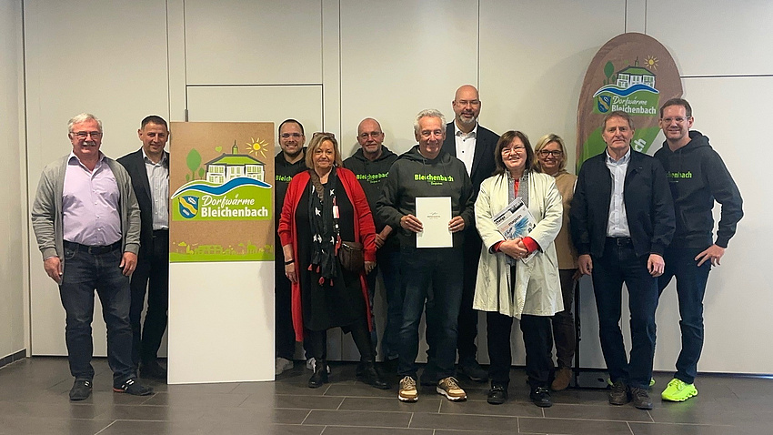 Elf Frauen und Männer gruppieren sich um ein Plakat.