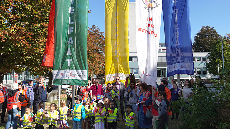 Gruppenfoto vor den gehissten Flaggen