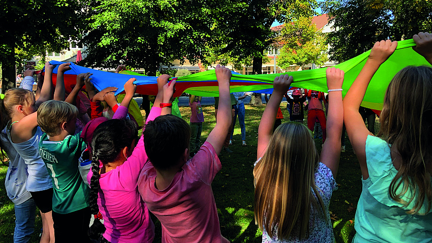 Eine Gruppe Kinder schwingt ein buntes Tuch