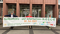Von links: Dr. Reinhold Merbs, Erste Kreisbeigeordnete und Sozialdezernentin Stephanie Becker-Bösch und Anette Obleser. Alle halten ein 6 m langes Banner, welches auf die Selbsthilfe-MEILE hinweist. Von links: Dr. Reinhold Merbs, Erste Kreisbeigeordnete und Sozialdezernentin Stephanie Becker-Bösch und Anette Obleser. Alle halten ein 6 m langes Banner, welches auf die Selbsthilfe-MEILE hinweist.