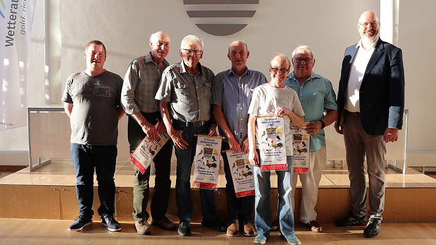 Mehrere Menschen halten Urkunden in den Händen.