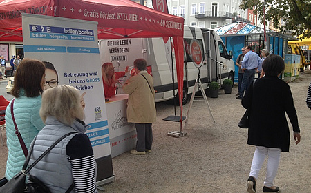 Ein Zelt auf einem Kiesweg. Daneben ein, Aufstelle, der über die Möglichkeit zum Hörtest informiert.