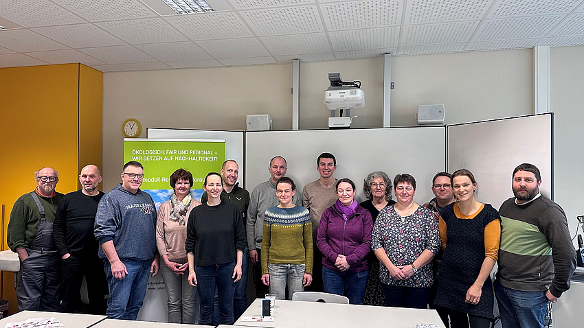 Mehrere Personen in einem Sitzungsraum. Im Hintergrund eine Tafel.