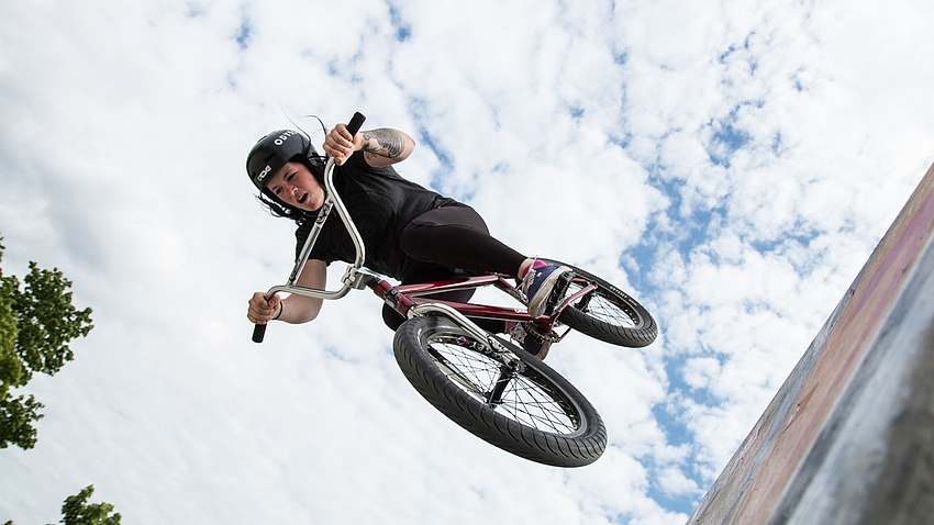 Ein Mädchen mit Helm fliegend auf einem Fahrrad