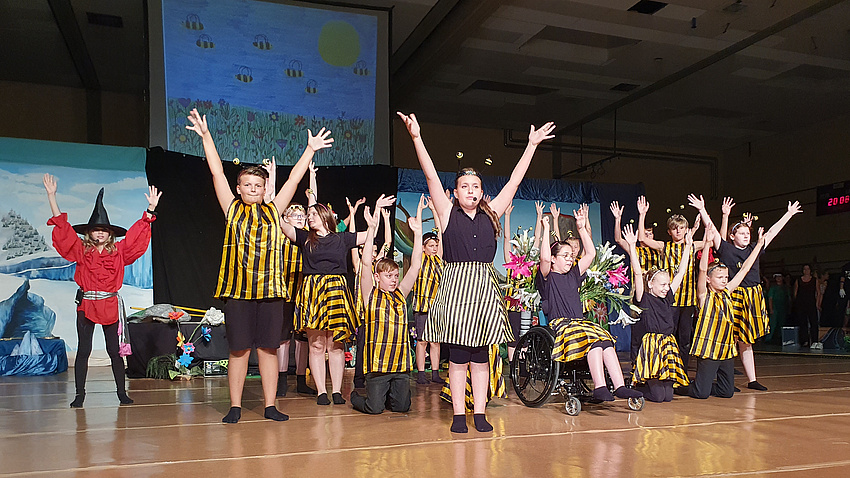 Eine große Gruppe von Kindern in Kostümen auf einer Bühne.