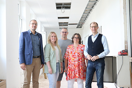 Fünf Personen stehen auf einer Baustelle.