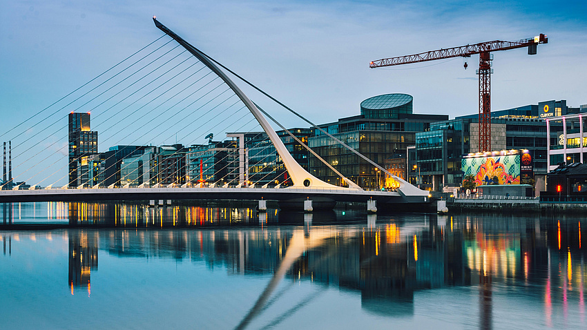 große weiße Betonbrücke zu sehen und am Ufer stehen viele moderne Gebäude