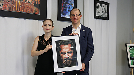 Landrat Jan Weckler und die Künstlerin Silvia Schmitt präsentieren eine Zeichnung.