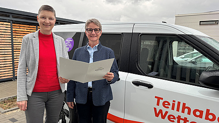 Zwei Menschen stehen vor einem Auto.